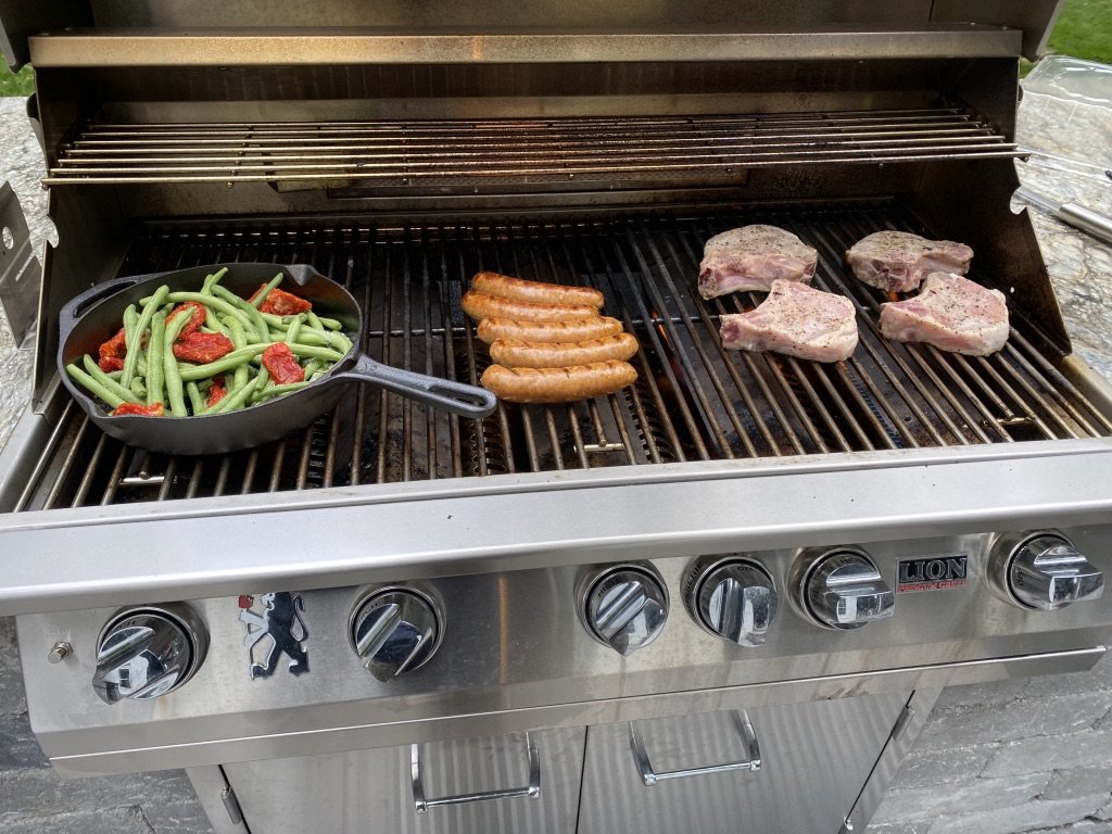 Garden to table — green beans from the garden cooking in cast iron on the outdoor grill with pork chops