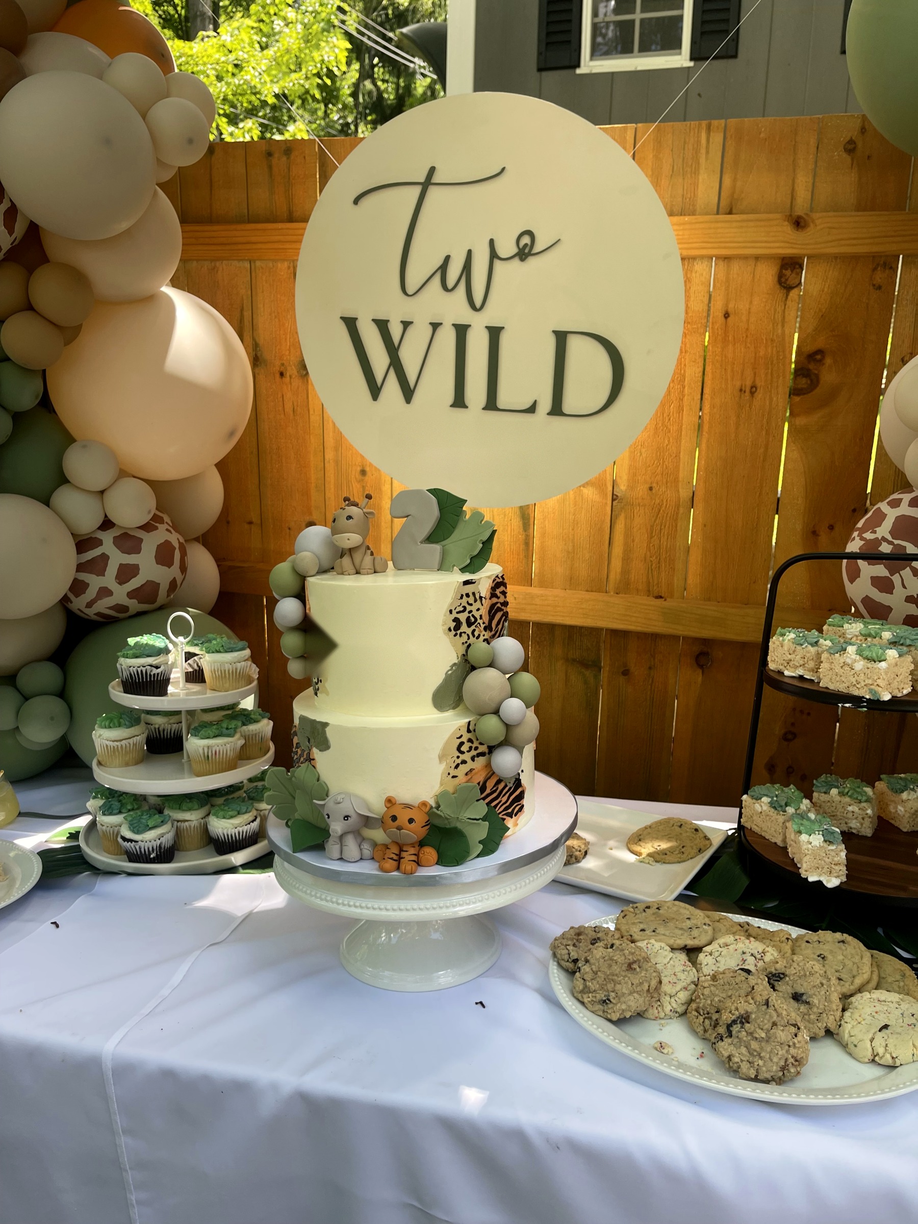 Two Wild safari second birthday dessert table with balloon arch and giraffe topper cake